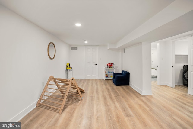 living area with light wood finished floors, visible vents, washer / clothes dryer, and baseboards