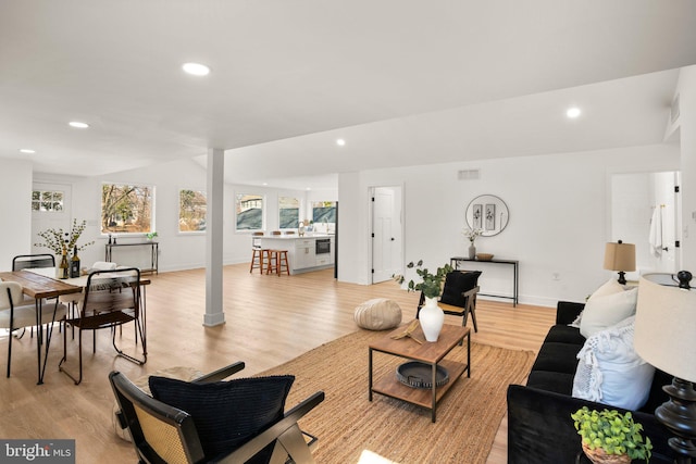 living room with lofted ceiling, light wood-type flooring, visible vents, and recessed lighting