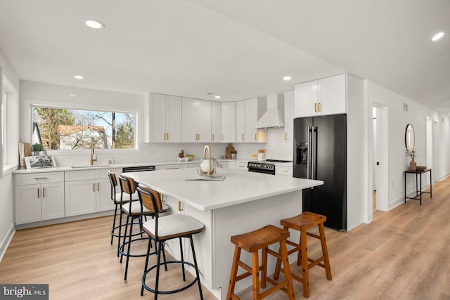 kitchen with white cabinetry, high end black refrigerator, custom exhaust hood, and a breakfast bar area