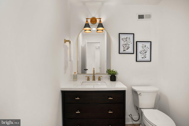 half bath featuring toilet, visible vents, and vanity