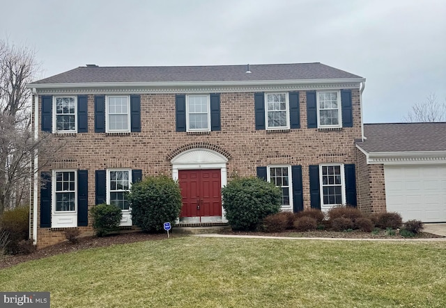 view of front facade featuring a garage, brick siding, a front lawn, and a shingled roof