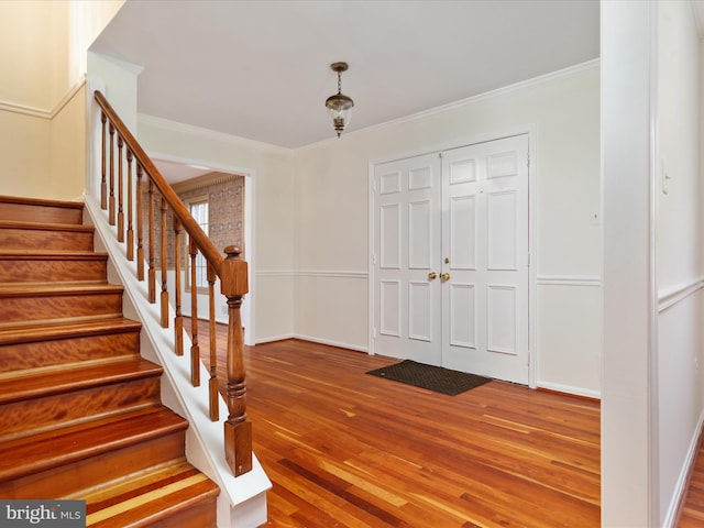 foyer featuring ornamental molding, stairs, baseboards, and wood finished floors