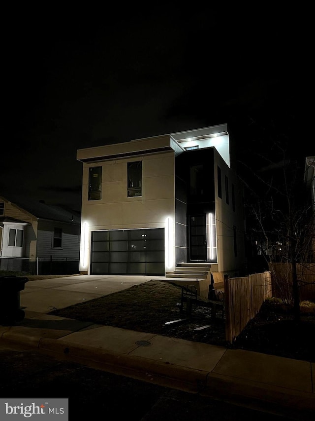 view of front of property with an attached garage, fence, driveway, and stucco siding