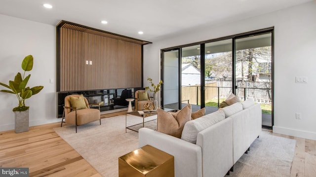 living area with baseboards, recessed lighting, and light wood-style floors