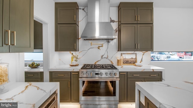 kitchen with backsplash, stainless steel range with gas cooktop, wall chimney range hood, and light stone counters