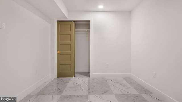 unfurnished bedroom featuring recessed lighting, marble finish floor, baseboards, and a closet