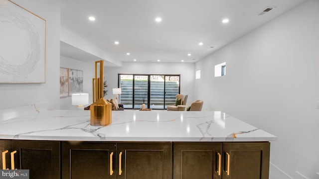 kitchen with dark brown cabinetry, visible vents, recessed lighting, and light stone counters