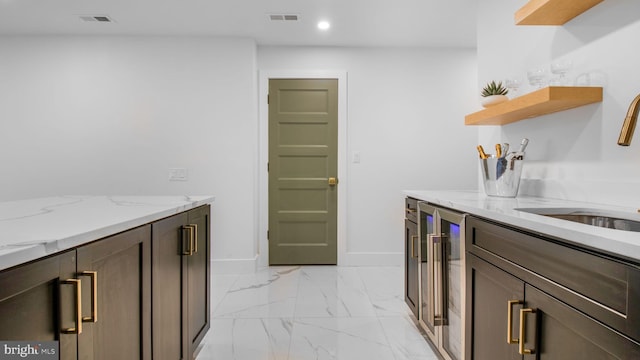 kitchen featuring marble finish floor, light stone counters, wine cooler, visible vents, and baseboards