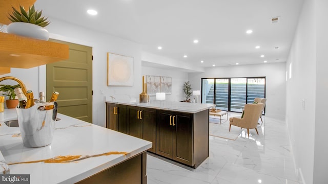 kitchen with light stone counters, dark brown cabinets, marble finish floor, a peninsula, and recessed lighting