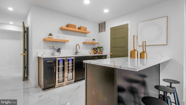 kitchen featuring a kitchen breakfast bar, visible vents, recessed lighting, light stone countertops, and beverage cooler