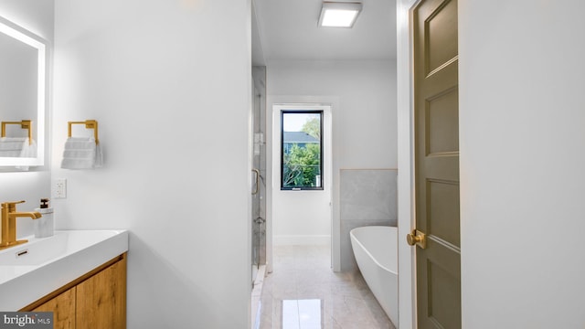 full bathroom featuring a soaking tub, a stall shower, baseboards, marble finish floor, and vanity