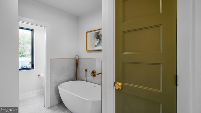 bathroom with a soaking tub and baseboards