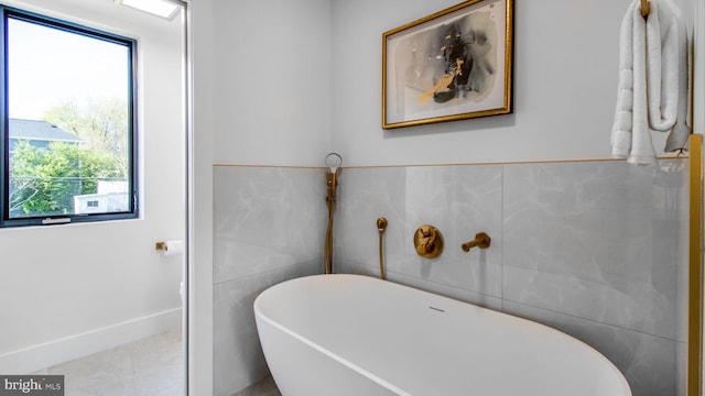 full bathroom with tile patterned flooring, a freestanding tub, and tile walls