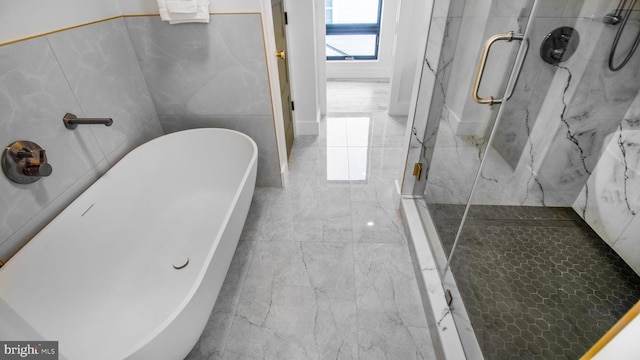 bathroom with a freestanding bath, marble finish floor, and a marble finish shower