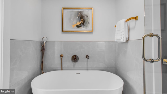 full bathroom featuring tile walls and a soaking tub