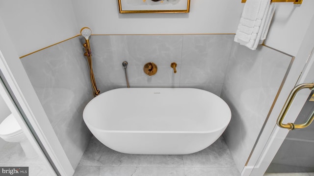 bathroom featuring a freestanding tub and tile walls
