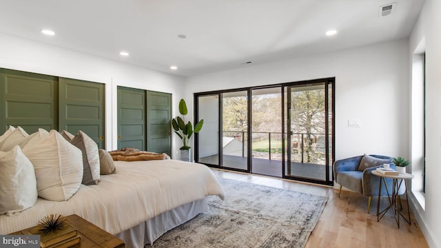 bedroom featuring two closets, light wood-style flooring, access to outside, visible vents, and recessed lighting
