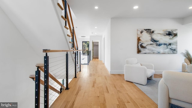 hallway featuring recessed lighting, baseboards, light wood-style floors, and an upstairs landing