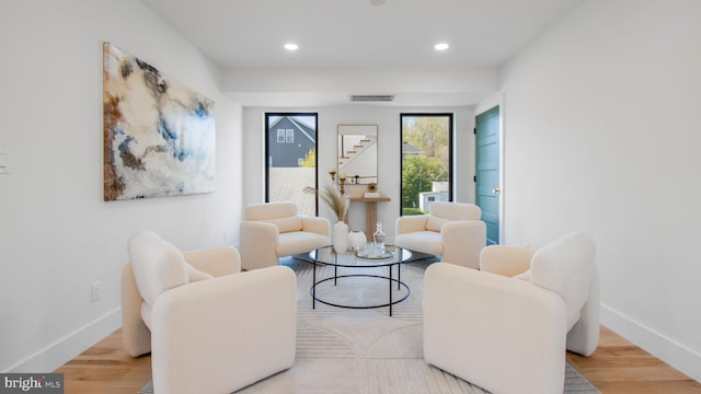living area with baseboards, wood finished floors, and visible vents