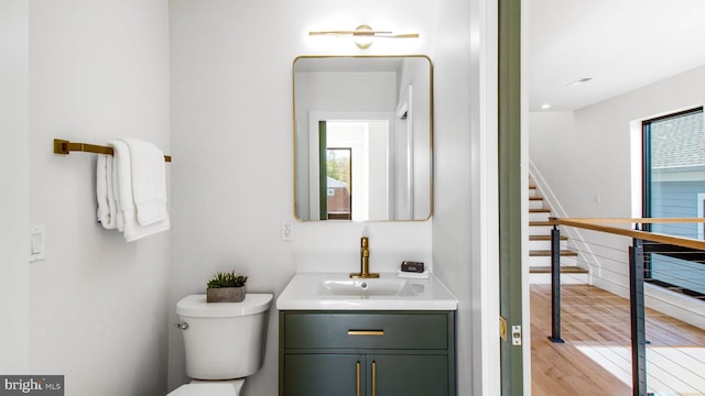 half bath featuring toilet, vanity, and wood finished floors