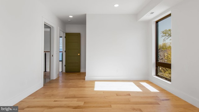 hallway featuring light wood-type flooring, visible vents, baseboards, and plenty of natural light