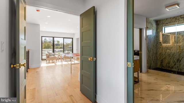 hall featuring recessed lighting, a healthy amount of sunlight, light wood finished floors, and baseboards