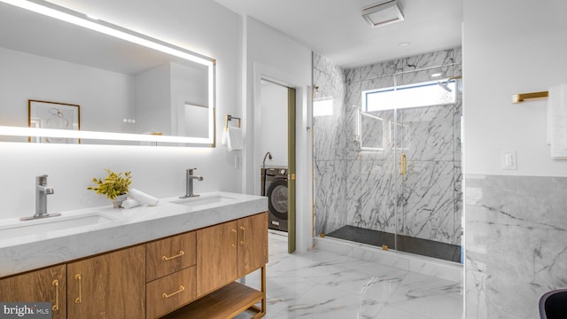 bathroom featuring a marble finish shower, a sink, marble finish floor, and washer / clothes dryer