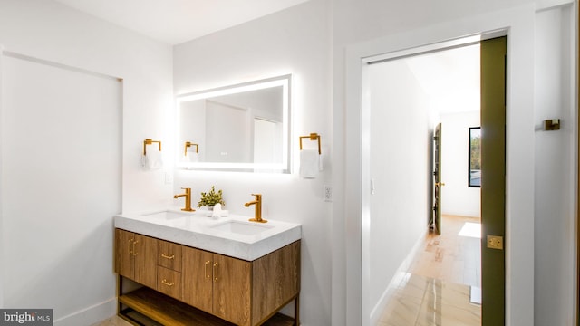 bathroom featuring baseboards, a sink, and double vanity
