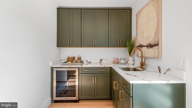 bar featuring a sink, wet bar, light wood-style flooring, baseboards, and wine cooler