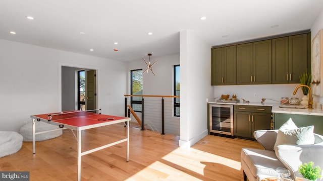game room featuring a sink, beverage cooler, light wood-style floors, indoor wet bar, and recessed lighting