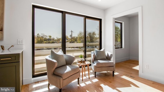 sitting room with light wood-style floors, visible vents, and baseboards