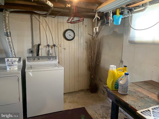 laundry room with laundry area, separate washer and dryer, and wood walls