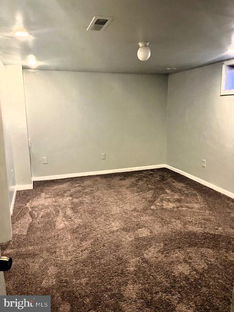 finished below grade area featuring carpet, visible vents, and baseboards