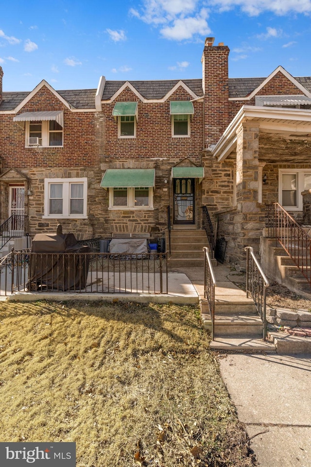 view of front facade with stone siding, a chimney, and a patio area