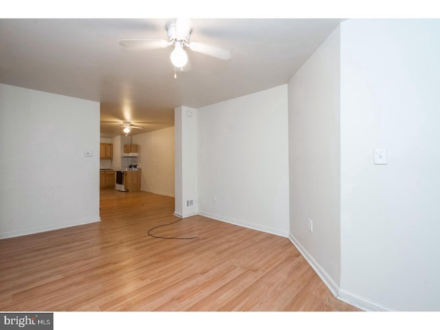 unfurnished room featuring a ceiling fan, visible vents, light wood-style flooring, and baseboards