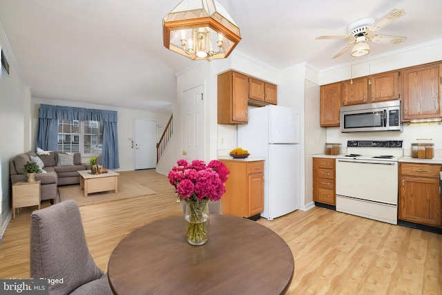 kitchen featuring light wood finished floors, white appliances, light countertops, and crown molding