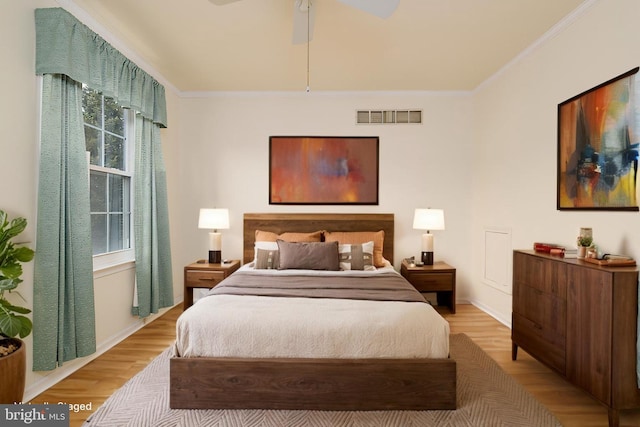 bedroom with visible vents, baseboards, light wood-style flooring, and crown molding