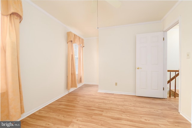 empty room with baseboards, light wood finished floors, and ornamental molding