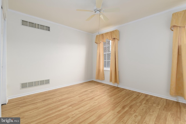 empty room with crown molding, light wood-style flooring, and visible vents