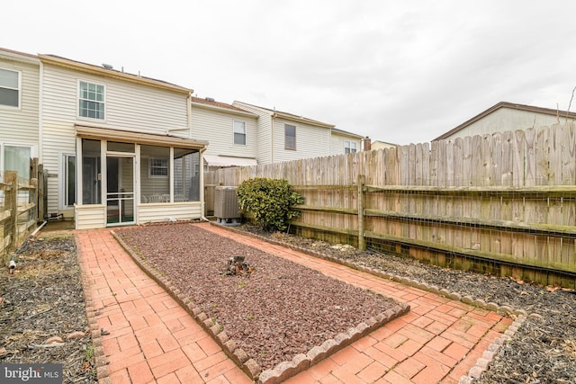 view of yard with central AC unit, a patio, a fenced backyard, and a sunroom