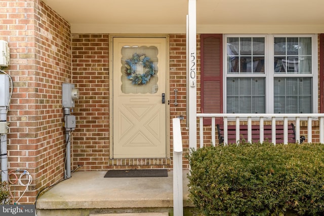 entrance to property featuring brick siding and covered porch