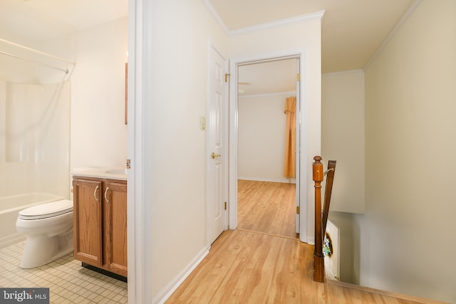 hallway featuring an upstairs landing, light wood-type flooring, and ornamental molding