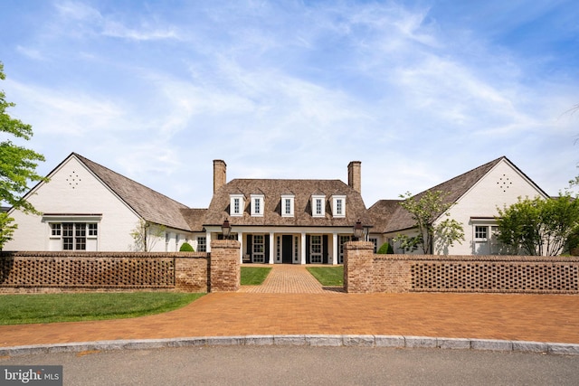 view of front of house with a fenced front yard, a chimney, and a front lawn