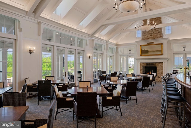 dining area with french doors, a fireplace, high vaulted ceiling, a chandelier, and beamed ceiling