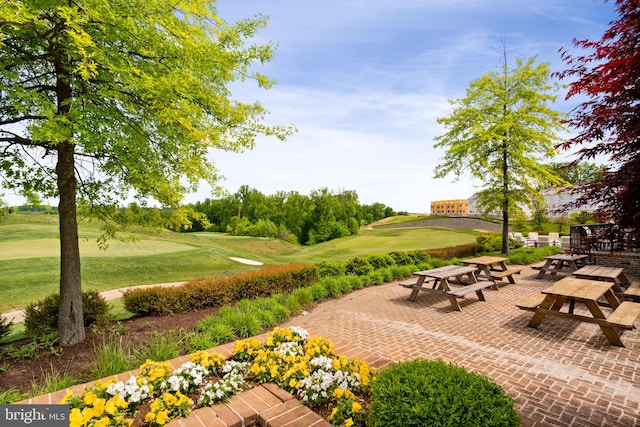 surrounding community featuring view of golf course, a patio area, and a yard