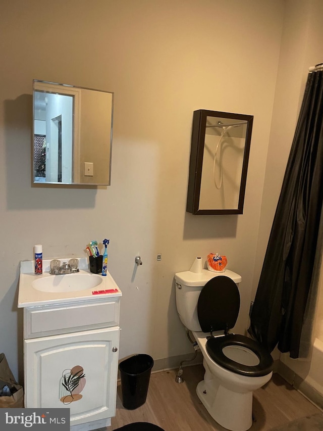 full bath with toilet, wood finished floors, vanity, and baseboards