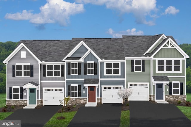 view of property featuring driveway, stone siding, and a garage