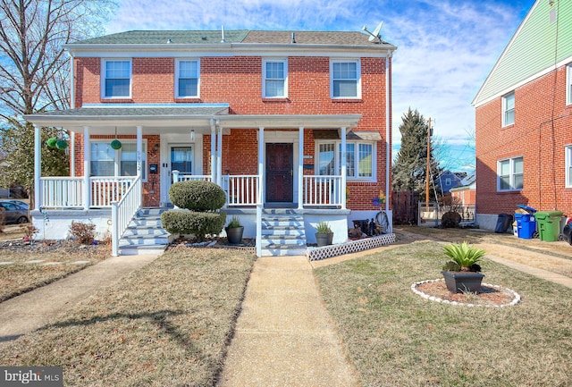 view of front of home with brick siding, a porch, and a front lawn