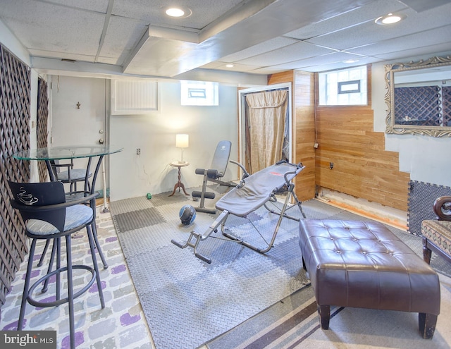 workout room featuring recessed lighting, a drop ceiling, and wood walls