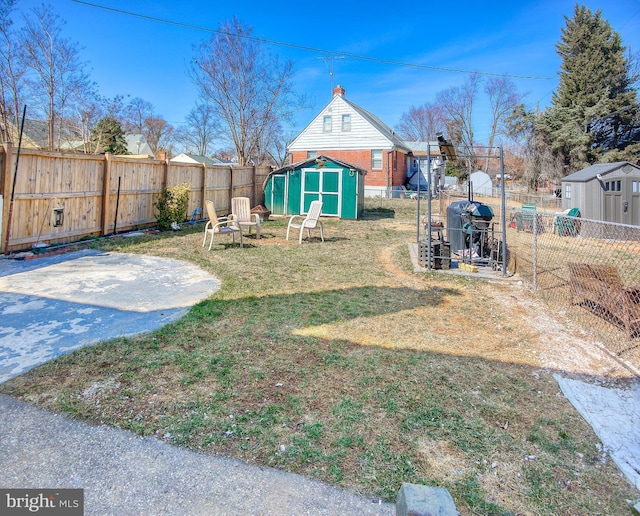 view of yard with an outbuilding, a fenced backyard, and a shed